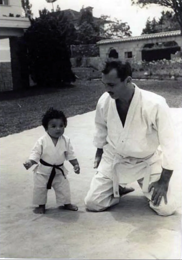 Helio Gracie kneeling beside a young child in a gi
